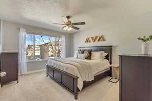 Bedroom featuring light carpet, ceiling fan, a textured ceiling, and baseboards