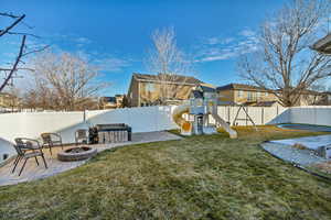 View of yard with a fire pit, a patio, a playground, and a fenced backyard