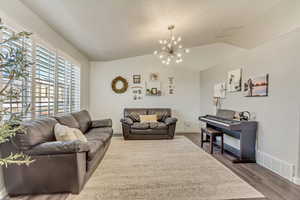 Living room featuring lofted ceiling, visible vents, and wood finished floors