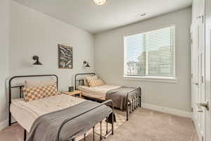 Bedroom with visible vents, light carpet, and baseboards