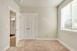 Unfurnished bedroom with a closet, light carpet, a sink, and baseboards