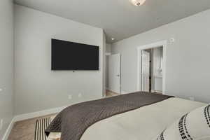 Bedroom featuring light carpet, baseboards, and ensuite bathroom