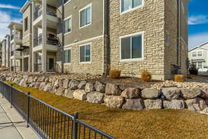 View of property exterior with a residential view, stone siding, fence, and stucco siding