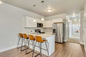 Kitchen featuring stainless steel appliances, a peninsula, light countertops, and white cabinetry