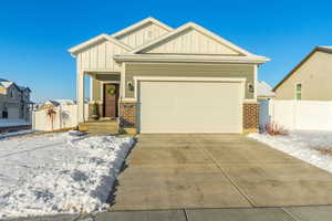 Craftsman inspired home with board and batten siding, brick siding, driveway, and fence