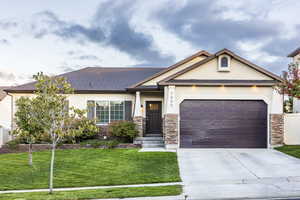 View of front of home featuring stone siding, driveway, and stucco siding