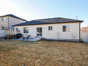 Back of house featuring entry steps, greenhouse, fence, a yard, and a patio area