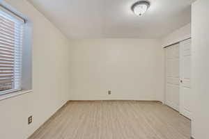 Unfurnished bedroom with wood finish floors, a closet, and multiple windows