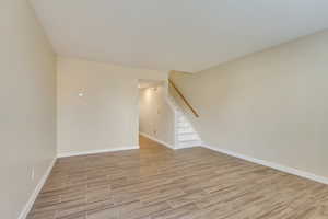 Spare room with baseboards, stairway, and wood finish floors