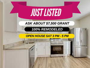 Kitchen with a sink, white cabinetry, light countertops, appliances with stainless steel finishes, and wood tiled floor