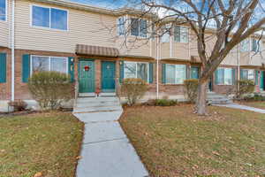 View of property with brick siding and a front lawn