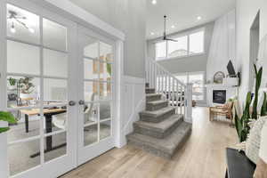 Staircase with french doors, a large fireplace, hardwood / wood-style floors, and a towering ceiling