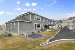 Back of property featuring a yard, central AC unit, a trampoline, and a playground