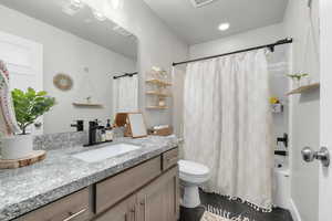 Full bathroom with toilet, a textured ceiling, vanity, shower / bath combo, and tile patterned flooring