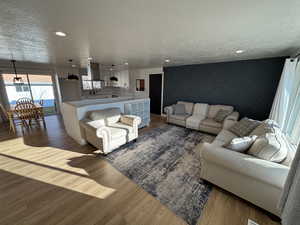 Living area featuring a textured ceiling, an accent wall, wood finished floors, and recessed lighting