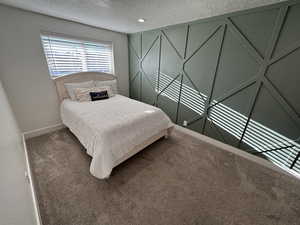 Carpeted bedroom featuring a textured ceiling and baseboards