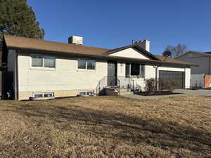 Ranch-style house with a garage, brick siding, driveway, a front lawn, and a chimney