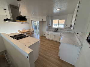 Kitchen featuring a sink, light wood-style flooring, black gas stovetop, and light stone countertops