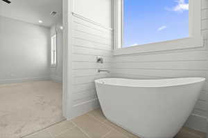Primary bathroom featuring tile patterned flooring and a freestanding soaking tub