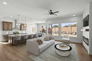 Living area with an electric fireplace, baseboards, light laminate floors, and recessed lighting. Virtually staged.