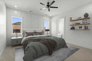 Primary bedroom with light colored carpet, a decorative wall and connected ensuite. Virtually staged.