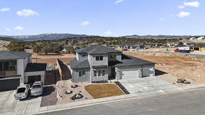 View of front facade featuring an attached garage, a mountain view, concrete driveway, stone siding, and a residential view