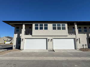 View of property with a garage, a balcony, and stucco siding