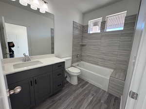 Bathroom with vanity, bathing tub / shower combination, toilet, and wood finished floors