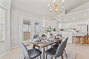 Dining space featuring recessed lighting, light carpet, vaulted ceiling, a chandelier, and baseboards