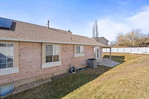 View of home's exterior with cooling unit, brick siding, fence, and roof with shingles