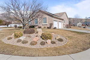 View of side of property featuring a yard, concrete driveway, brick siding, and an attached garage