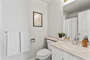 Bathroom with toilet, vanity, and baseboards