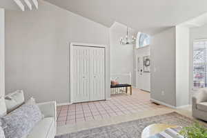 Living area featuring baseboards, light tile patterned floors, a high ceiling, and an inviting chandelier