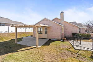 Back of property with a yard, brick siding, a patio area, and fence