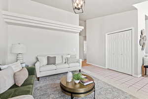 Tiled living area with baseboards and a chandelier