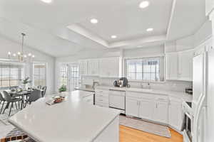 Kitchen featuring white appliances, white cabinetry, pendant lighting, and light countertops