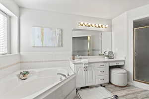 Full bathroom featuring a garden tub, vanity, a shower stall, and wood finished floors