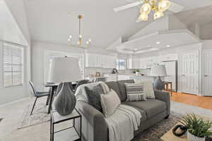 Living area with baseboards, wood finished floors, ceiling fan with notable chandelier, high vaulted ceiling, and recessed lighting