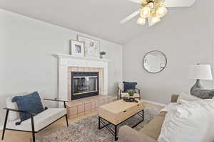 Living room featuring lofted ceiling, light carpet, a fireplace, and baseboards