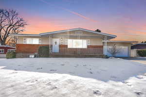 View of front of home featuring brick siding, a porch, and an attached garage