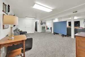 Interior space with a textured ceiling, carpet floors, and visible vents