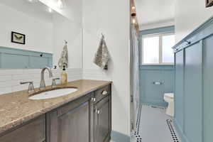 Bathroom featuring toilet, tile patterned floors, tasteful backsplash, and vanity