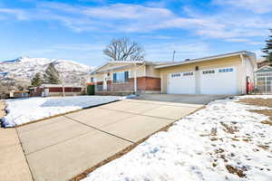 View of front of property with brick siding, covered porch, concrete driveway, an attached garage, and a mountain view