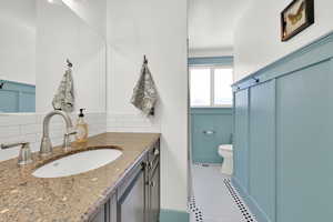 Bathroom with tile patterned floors, vanity, toilet, and decorative backsplash