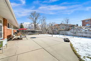 Snow covered patio featuring a fenced backyard and a mountain view