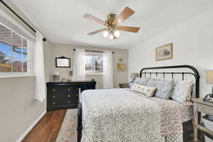 Bedroom with ceiling fan, baseboards, and dark wood-style flooring