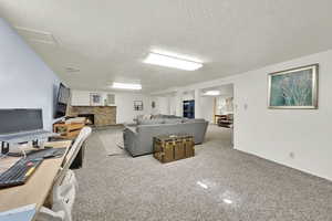 Carpeted living area featuring a brick fireplace and a textured ceiling