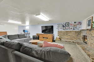 Living room with a textured ceiling, brick wall, and a brick fireplace