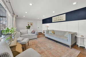 Living area featuring recessed lighting, wainscoting, a decorative wall, and wood finished floors