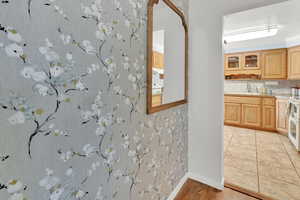 Interior space featuring light brown cabinets, a sink, light countertops, decorative backsplash, and glass insert cabinets